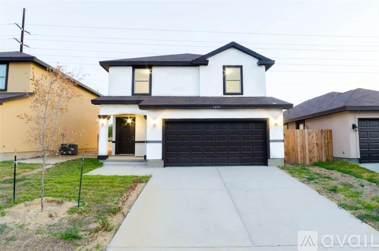 A modern two-story house with a black garage door is for sale.