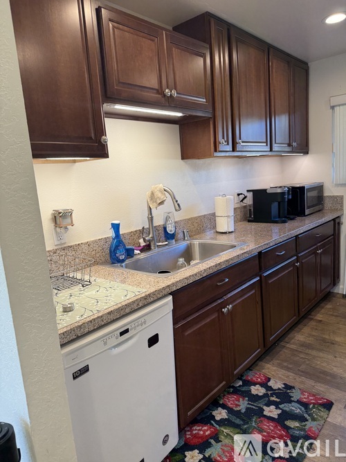 A kitchen with brown cabinets and a white dishwasher.