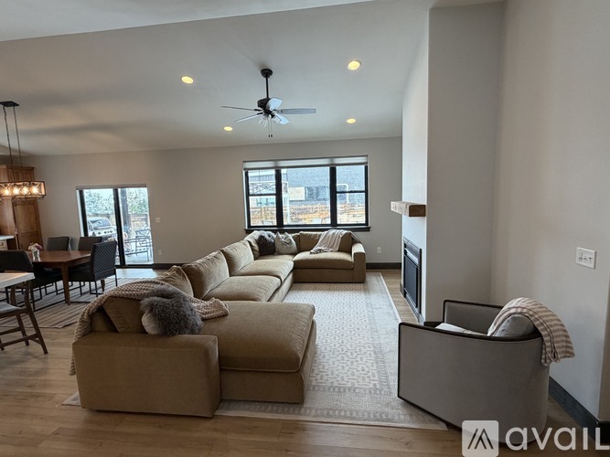 A spacious living room with wooden flooring and a modern chandelier.