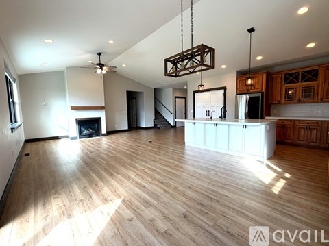 A spacious living room with wooden flooring and a modern chandelier.