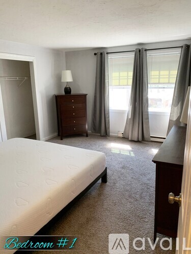 A bedroom with a bed, dresser, and window with curtains.