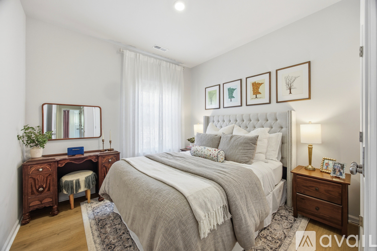 A bedroom with a large bed, a wooden desk with a mirror, and a dresser with a lamp.