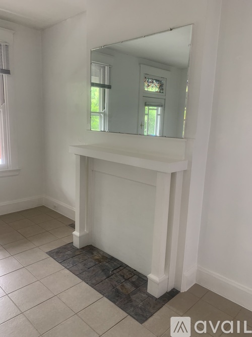 A white fireplace with a mirror above it in a room.