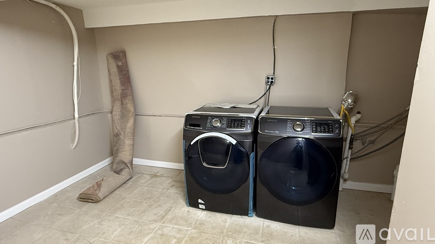 A laundry room with two washing machines and a dryer.