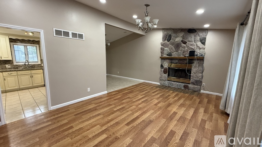A spacious room with wooden flooring and a stone fireplace.
