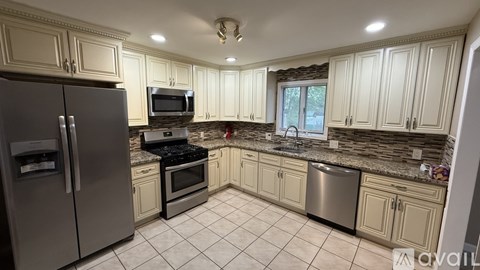 A kitchen with a refrigerator, microwave, oven, and sink.
