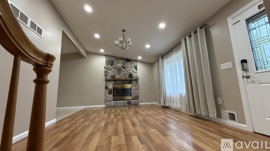 A spacious living room with wood flooring and a stone fireplace.