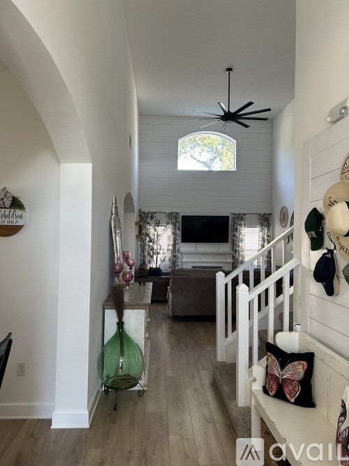A living room with a staircase and a ceiling fan.