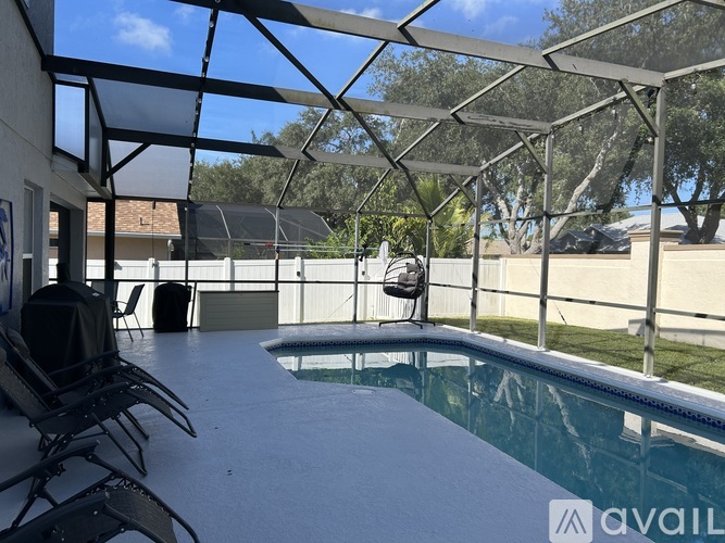 A pool under a glass roof with chairs around it.