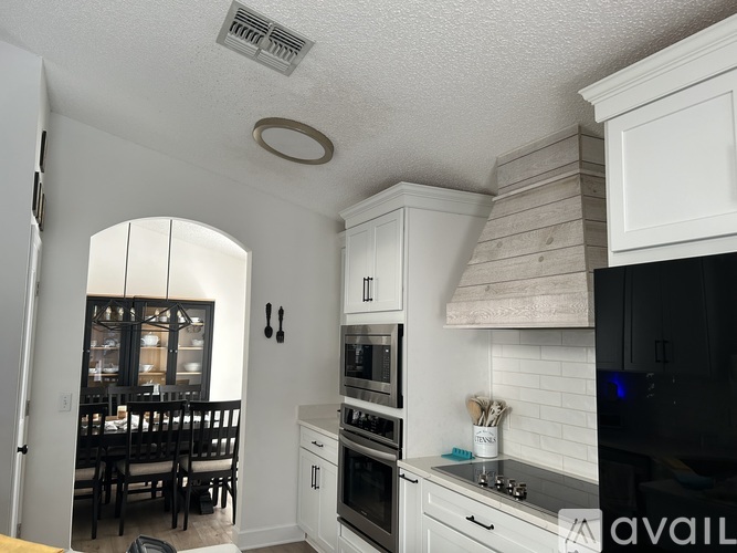 A kitchen with white cabinets and a black refrigerator.