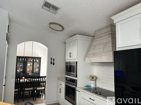 A kitchen with white cabinets and a black refrigerator.
