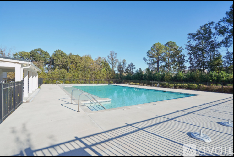 A pool surrounded by trees and a white building.