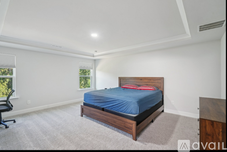 A bedroom with a bed, chair, and window.