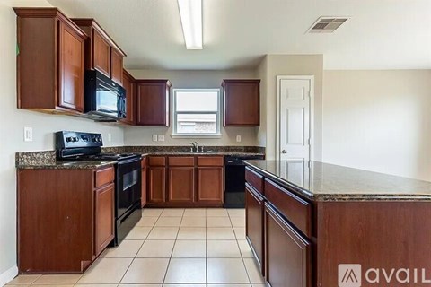 A kitchen with brown cabinets and black appliances.