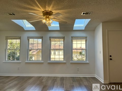 A room with a ceiling fan and skylights.