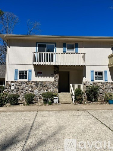 A two-story house with a balcony and a stone wall.