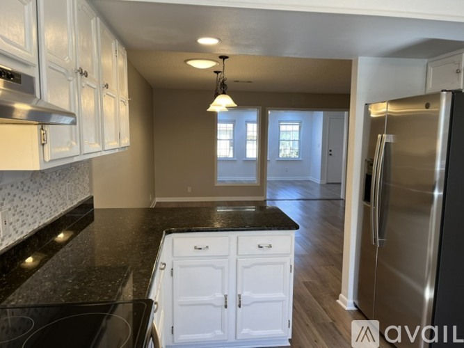 A kitchen with white cabinets and a black countertop.