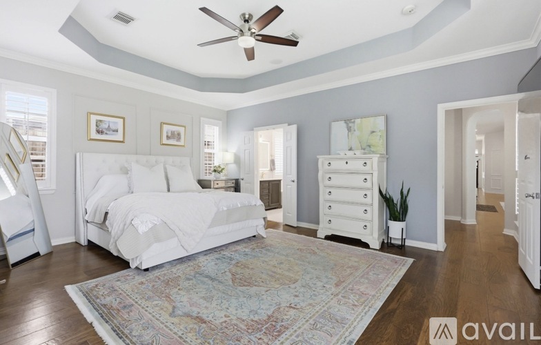 A bedroom with a white bed and a ceiling fan.