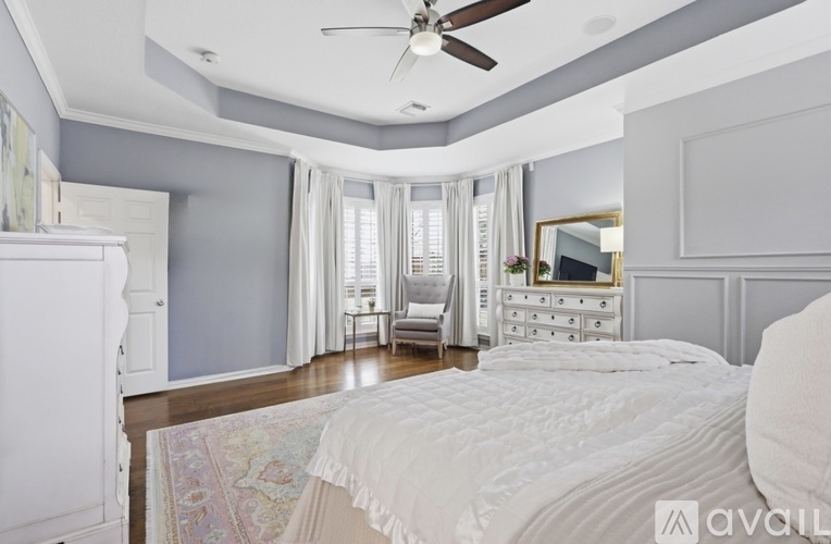 A bedroom with a large bed, a dresser, and a ceiling fan.