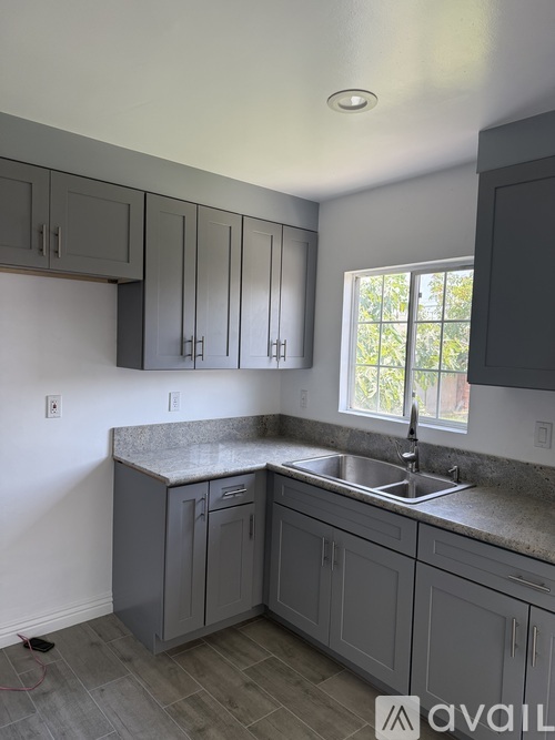 A kitchen with grey cabinets and a granite countertop.