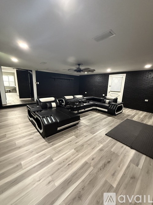 A modern living room with a black couch and wooden flooring.