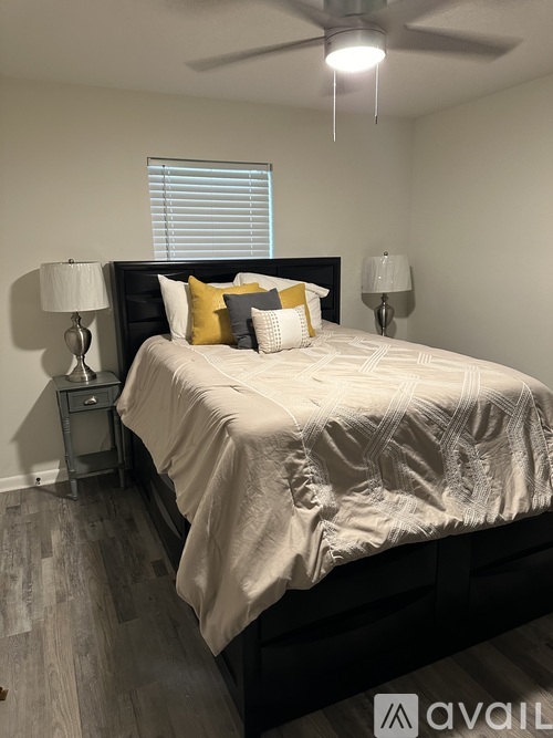 A bedroom with a bed, two lamps, and a ceiling fan.