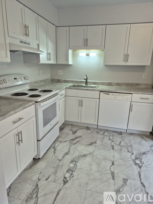 A kitchen with white cabinets and a marble floor.