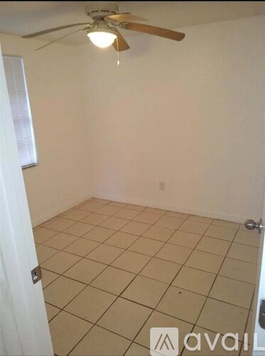 A room with a ceiling fan and tiled floor.