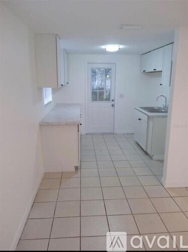 A kitchen with white cabinets and a white door.