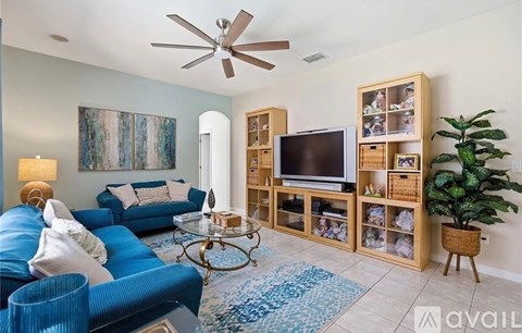 A living room with a blue couch and a television on a stand.