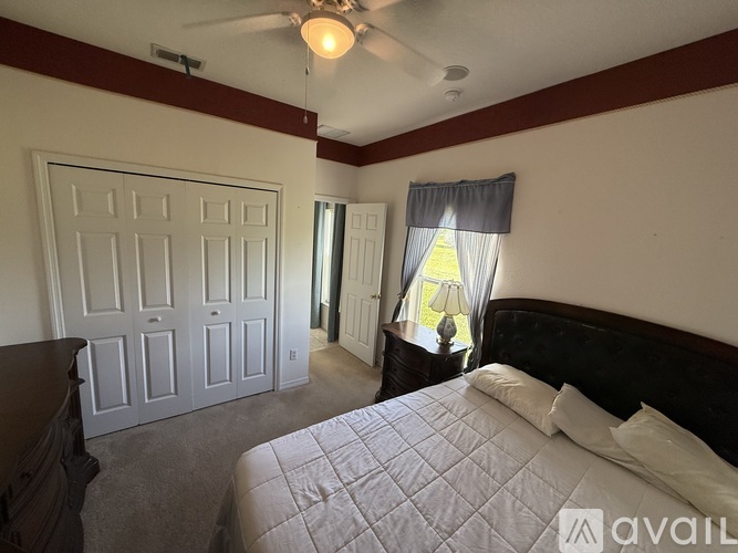 A bedroom with a bed, dresser, and window.