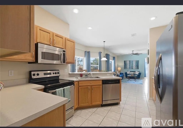 A kitchen with a refrigerator, oven, microwave, and sink.