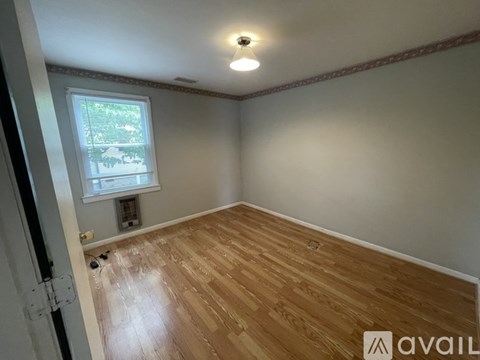 A room with wooden flooring and a window.