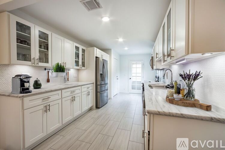 A kitchen with white cabinets and a marble countertop.
