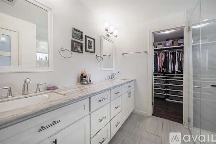 A bathroom with a double sink vanity and a walk-in closet.