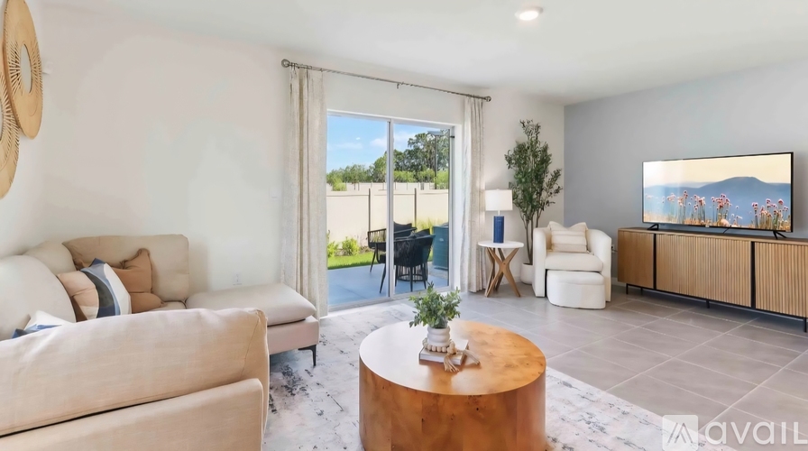 A living room with a large window, a sofa, a coffee table, and a TV.