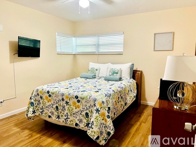 A bedroom with a bed, a television, and a lamp.