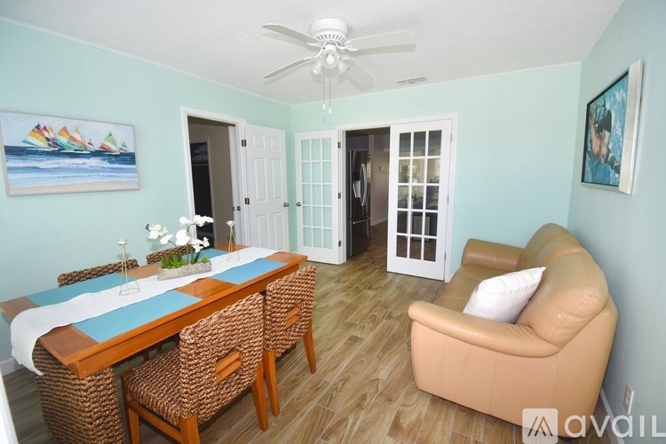 A dining room with a table set for two and a couch.