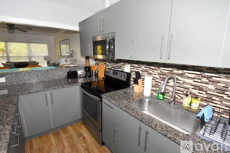 A kitchen with a black stove top oven and a granite counter top.