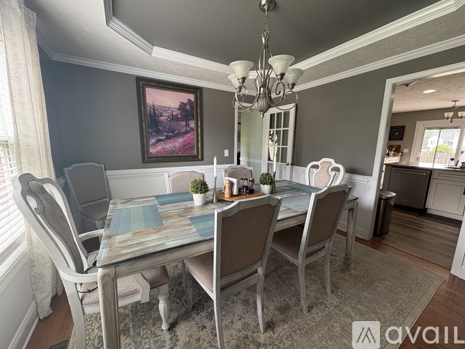 A dining room with a table set for four and a chandelier hanging from the ceiling.
