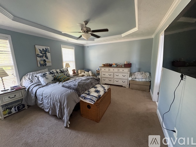 A bedroom with a bed, dresser, and a ceiling fan.
