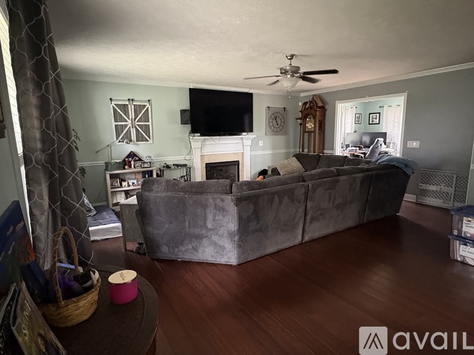 A living room with a grey couch and a television on the wall.