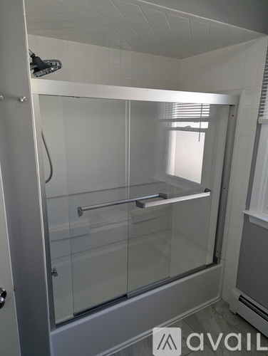 A shower with a glass door and a metal handle.