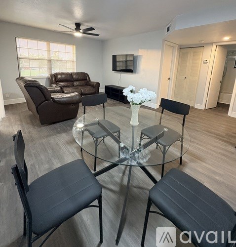A living room with a glass table and black chairs.