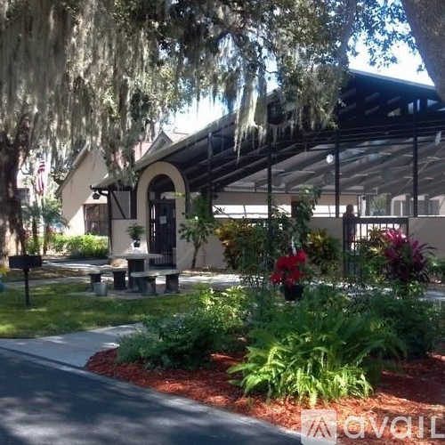 A building with a black roof and a white entrance is surrounded by greenery.