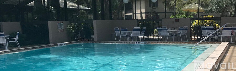 A pool with blue water and chairs around it.