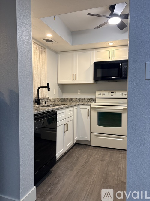 A kitchen with white cabinets and a black stove top oven.