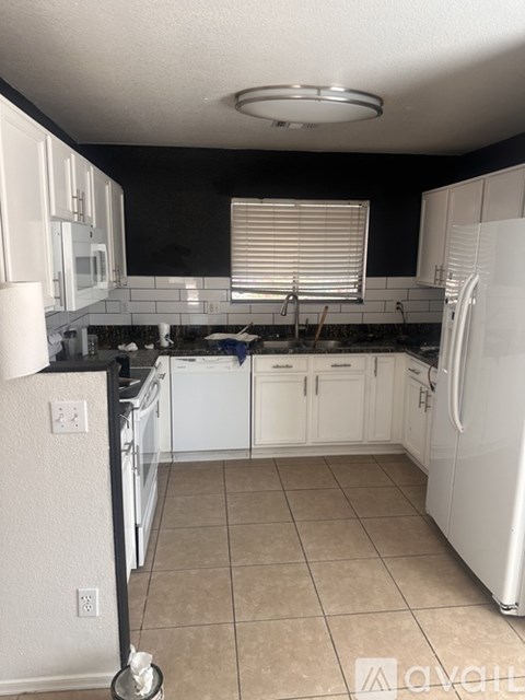 A kitchen with white appliances and black countertops.