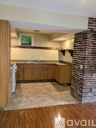 A kitchen with wooden cabinets and a brick pillar.