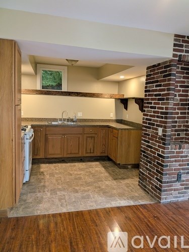 A kitchen with wooden cabinets and a brick pillar.